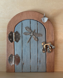 light blue handcrafted faerie door with dragonfly and brown frame