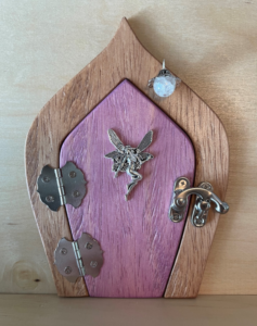light pink handcrafted faerie door with faerie charm and brown frame