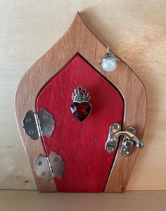 red handcrafted faerie door with red jewel charm and brown frame
