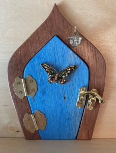 ocean blue handcrafted faerie door with butterfly and brown frame