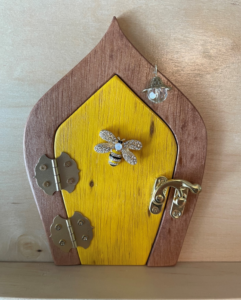 yellow handcrafted faerie door with bumble bee and brown frame