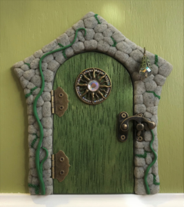 green handcrafted faerie door with stone frame