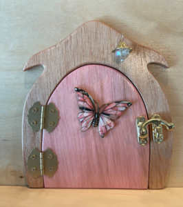 light pink handcrafted faerie door with butterfly charm and brown frame