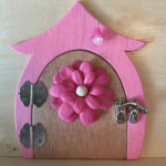 brown handcrafted faerie door with pink flower and pink frame