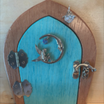 light turquoise handcrafted faerie door with moon charm and brown frame