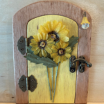 yellow handcrafted faerie door with sunflowers and brown frame