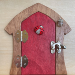 red handcrafted faerie door with ladybug charm and brown frame