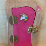 pink handcrafted faerie door with unicorn charm and brown frame