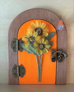 orange handcrafted faerie door with sunflowers and brown frame