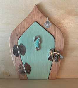 light aqua handcrafted faerie door with seahorse and brown frame