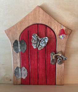 red handcrafted faerie door with butterfly charm and brown frame