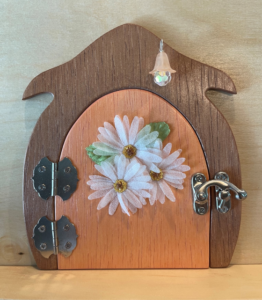light orange handcrafted faerie door with flowers and brown frame