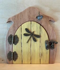 Light yellow handcrafted faerie door with dragonfly charm and brown frame