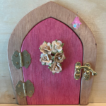 pink handcrafted faerie door with flowers and brown frame