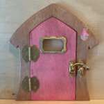 pink handcrafted faerie door with window and brown frame