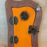 orange handcrafted faerie door with sun charm and brown frame
