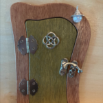 olive green handcrafted faerie door with a charm and brown frame